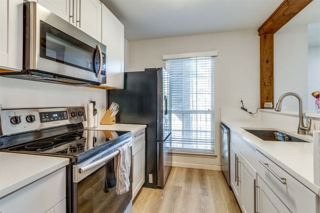 Kitchen with a sink, light wood-style floors, stainless steel appliances, light countertops, and white cabinetry | Image 9