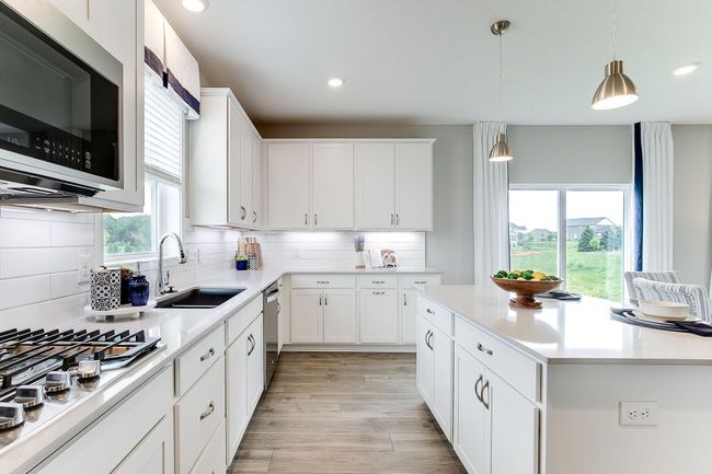 The signature kitchen in the Jordan floorplan is beautifully designed & includes quartz countertops, tile backsplash, double wall ovens & a huge walk-in pantry. The kitchen is a chef's dream & provides ample space for your culinary needs. | Image 7
