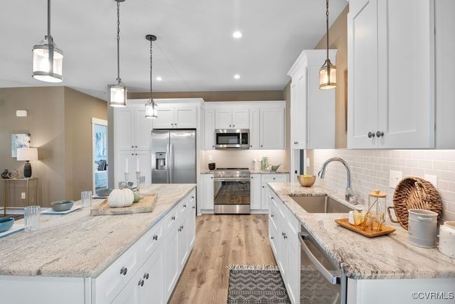 Kitchen featuring light wood-style flooring, tasteful backsplash, white cabinets, appliances with stainless steel finishes, and a sink | Image 10