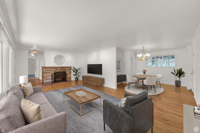 Living room with a chandelier, wood finished floors, a fireplace, and track lighting | Image 12