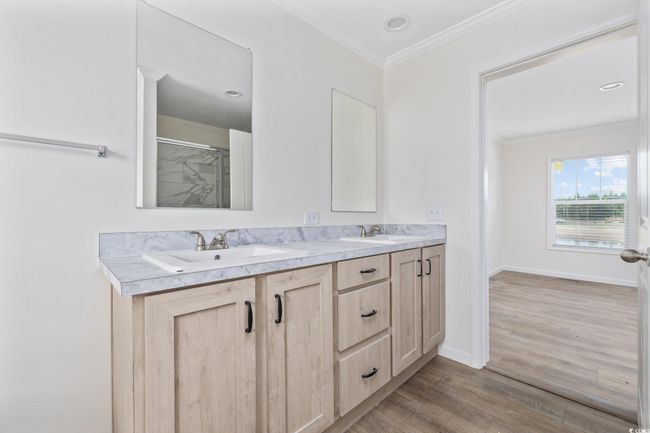 Bathroom with wood finished floors, double vanity, an enclosed shower, and crown molding | Image 28