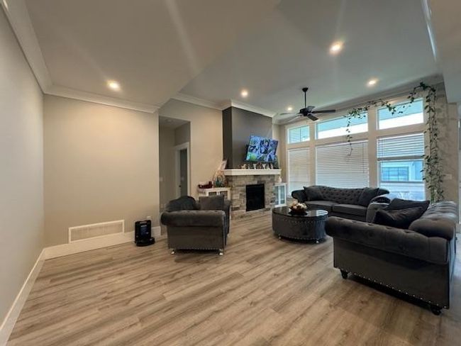 Living area with baseboards, a ceiling fan, wood finished floors, and visible vents | Image 17