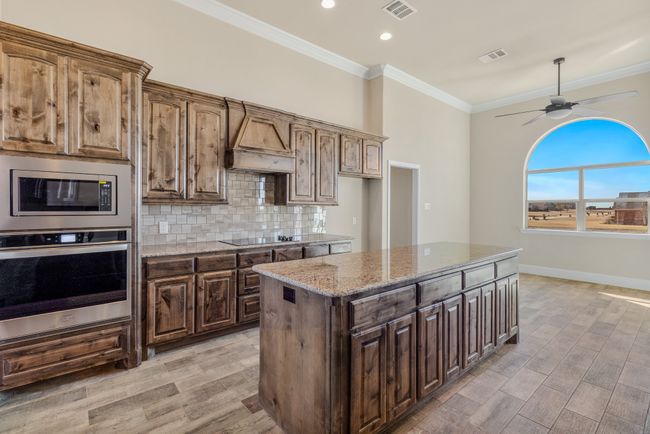 Kitchen with stainless steel appliances, light stone countertops, ornamental molding, a ceiling fan, and tasteful backsplash | Image 26
