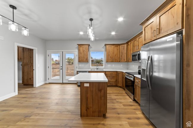 Kitchen featuring light countertops, a sink, a kitchen island, light wood finished floors, and appliances with stainless steel finishes | Image 15