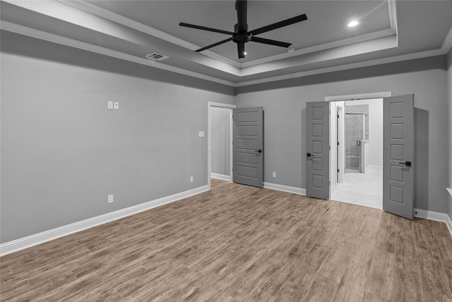 Unfurnished bedroom with ornamental molding, a tray ceiling, wood finished floors, recessed lighting, and a ceiling fan | Image 16