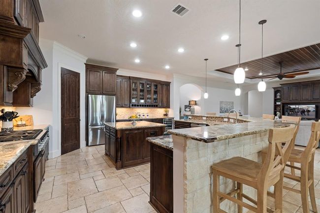 Notice how the stately cabinets perfectly play off the wood paneled ceiling in the Living Room just beyond. There is that consistency again we were talking about. The Kitchen Island adds additional counter space for effortless prep work, and also boasts electrical outlets and an abundance of underneath storage. | Image 17