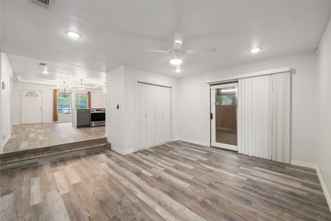 Unfurnished living room featuring wood finished floors, ceiling fan, baseboards, a chandelier, and recessed lighting | Image 11