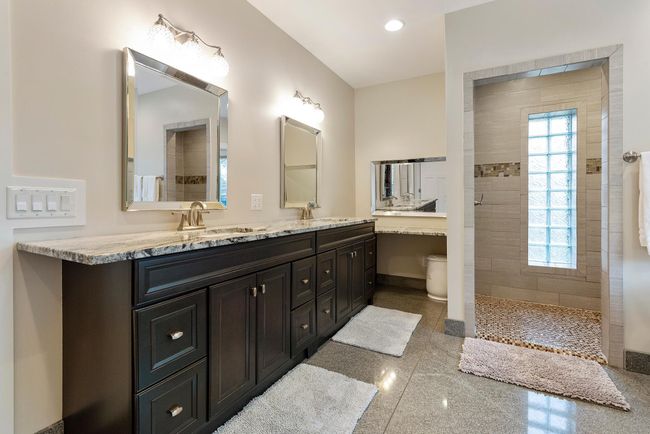 Exquisite primary bath with double sinks, makeup table, and no shortage of high end finishes down to the heated granite floors. | Image 22