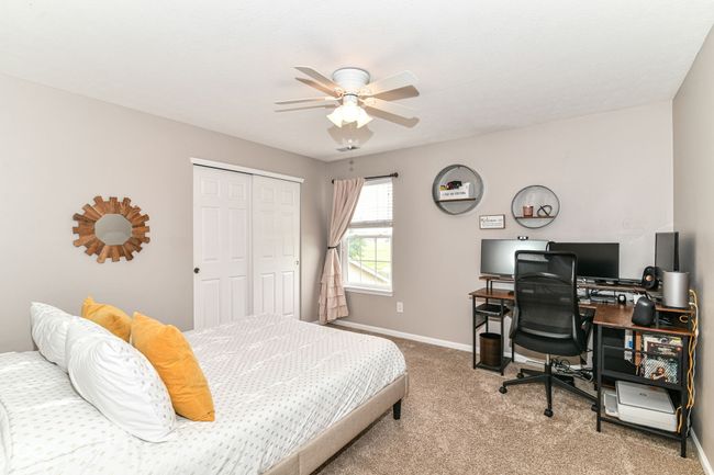 bedroom featuring light colored carpet, a closet, baseboards, a desk, and a ceiling fan | Image 25