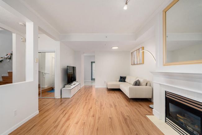Living room with light wood-style flooring, a fireplace, crown molding, and stairs | Image 5