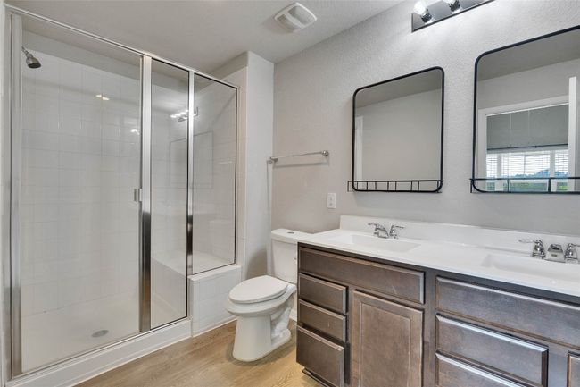 Private bath with double vanity and walk-in shower with a bench seat. | Image 9