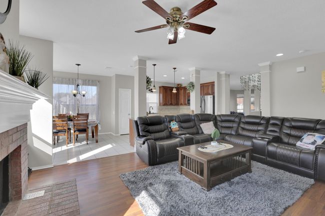 Living room with recessed lighting, a fireplace, light wood-style flooring, and ceiling fan with notable chandelier | Image 9