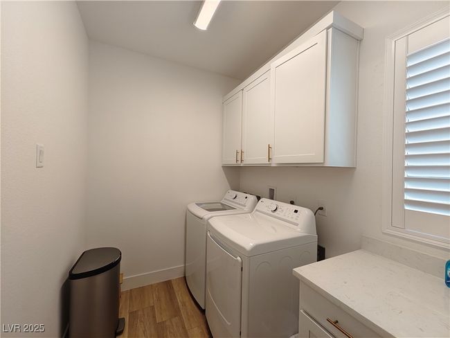 Laundry room featuring a healthy amount of sunlight, separate washer and dryer, cabinet space, and light wood-style flooring | Image 39