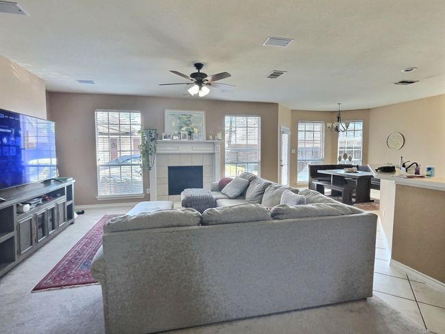 Living room featuring plenty of natural light, baseboards, a ceiling fan, and a chandelier | Image 5