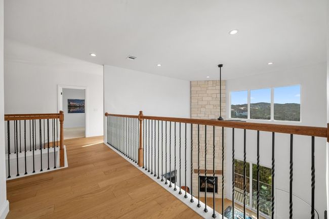 Stunning wood floors complement the gorgeous wood railings, overlooking the spacious family living area. A well-designed layout provides ample walking space leading to the bedrooms, media room, and recreational room, enhancing both style and functionality. | Image 22