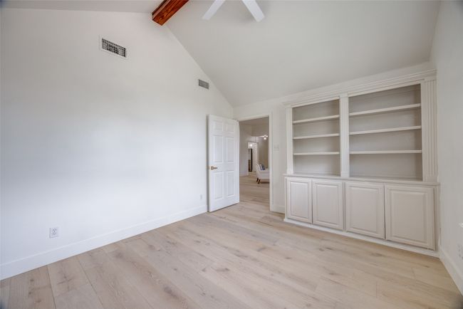 Empty room featuring beamed ceiling, light wood finished floors, a ceiling fan, and high vaulted ceiling | Image 24