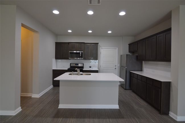 Kitchen with stainless appliances, tiled backsplash, kitchen island with sink | Image 11
