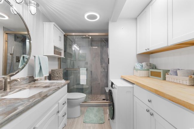 Full bath with washer / clothes dryer, vanity, a stall shower, and toilet | Image 22