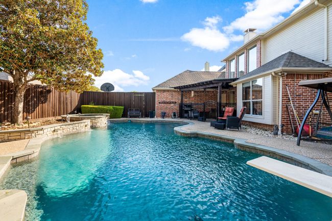 View of pool with a fenced backyard, a diving board, a patio, and a pool with connected hot tub | Image 31