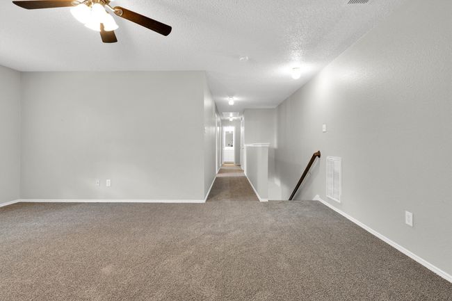 Unfurnished room featuring carpet floors, a textured ceiling, ceiling fan, and baseboards | Image 23
