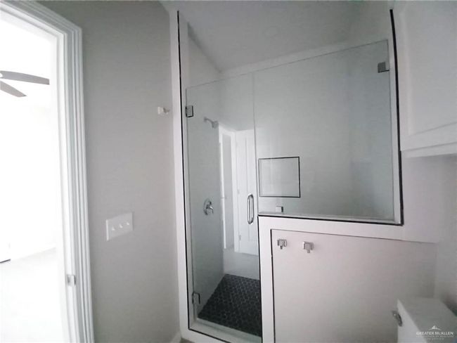 Full bathroom featuring a stall shower, ceiling fan, and toilet | Image 10