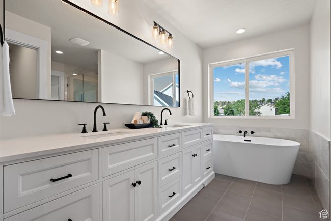 Primary bath featuring double vanity, a freestanding soaker tub, tile patterned flooring, recessed lighting, and a shower with shower door | Image 22