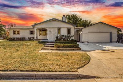 View of front of home with covered porch, a lawn, and a garage | Image 1