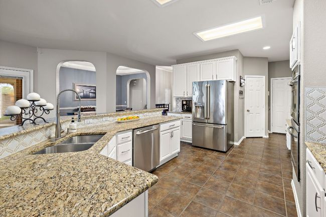 Kitchen with stainless steel appliances, a sink, arched walkways, white cabinetry, and recessed lighting | Image 12