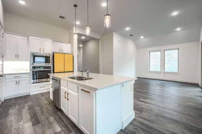 Kitchen with appliances with stainless steel finishes, a sink, dark wood finished floors, white cabinets, and vaulted ceiling | Image 11