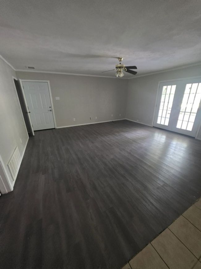 Unfurnished living room with crown molding, a ceiling fan, and dark wood finished floors | Image 11