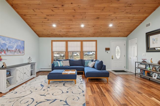 Living area featuring hardwood / wood-style floors, baseboards, visible vents, a baseboard radiator, and wooden ceiling | Image 11