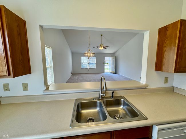 kitchen featuring dishwasher, light countertops, lofted ceiling, a ceiling fan, and a sink | Image 6