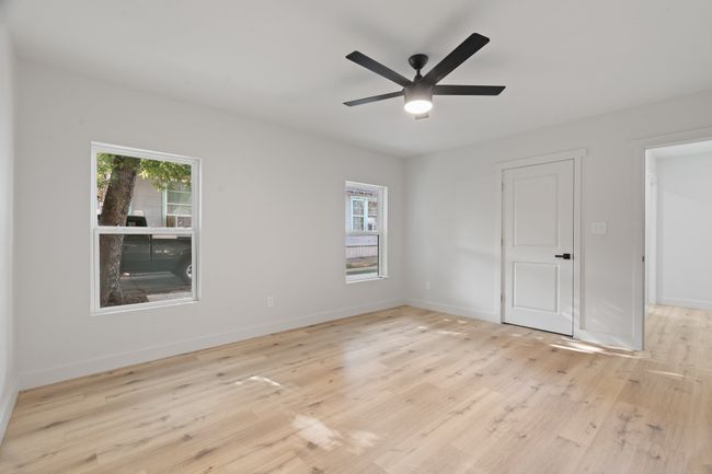 Unfurnished bedroom featuring multiple windows, light wood finished floors, baseboards, and ceiling fan | Image 15