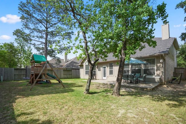 This angle highlights the spaciousness of the yard, offering plenty of room for outdoor activities, gardening, or relaxing under the shade of mature trees. | Image 34