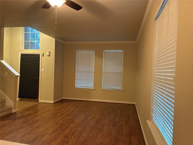 Empty room with wood finished floors, a ceiling fan, stairs, and ornamental molding | Image 4