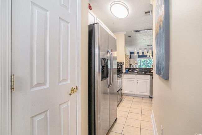 Washroom featuring a textured ceiling, washing machine and dryer, light tile patterned flooring, and cabinet space | Image 11