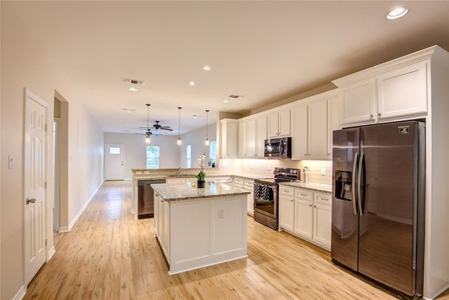 Kitchen featuring appliances with stainless steel finishes, a peninsula, light wood-style floors, white cabinets, and tasteful backsplash | Image 11