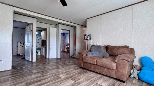 Living room featuring wood finished floors, ceiling fan, crown molding, a decorative wall, and a textured ceiling | Image 16