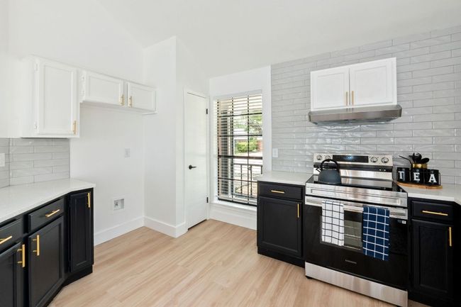 Kitchen featuring light countertops, under cabinet range hood, white and dark cabinetry, and stainless steel range with electric stovetop | Image 15