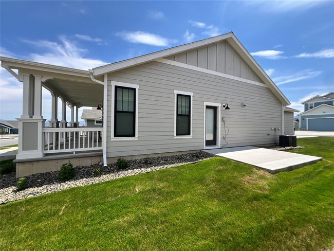 Side of house featuring a lawn, covered porch, central air condition unit, board and batten siding, and a patio | Image 5