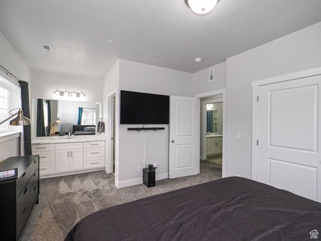 Bedroom featuring baseboards, connected bathroom, visible vents, and dark colored carpet | Image 20