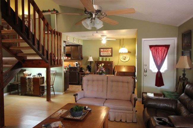 Living room featuring ceiling fan, lofted ceiling, light wood-style flooring, and stairway | Image 8