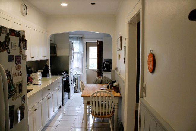 Kitchen featuring stainless steel appliances, arched walkways, light countertops, light tile patterned floors, and white cabinets | Image 6