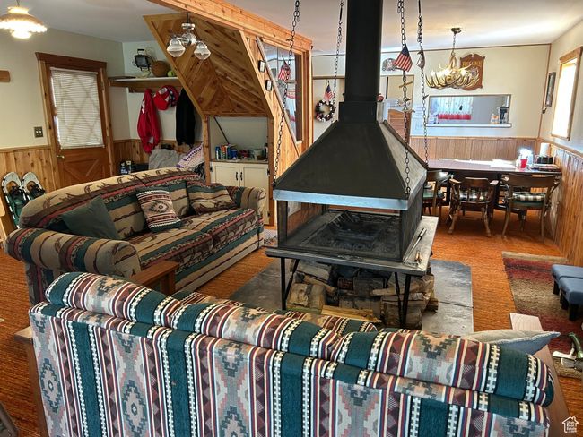 Living area with a wainscoted wall, a wood stove, wood walls, and a chandelier | Image 16