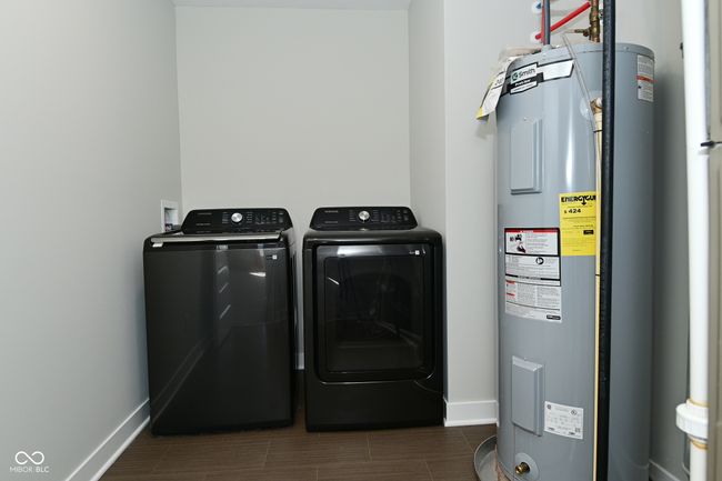 clothes washing area with laundry area, water heater, wood tiled floor, baseboards, and washing machine and dryer | Image 38