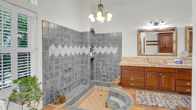 Full bath featuring a tile shower, backsplash, a notable chandelier, and vanity | Image 27