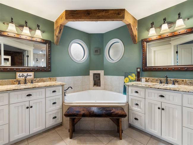 The owner's bath has a large corner soaking tub, double granite vanities, and a walk-in shower | Image 6