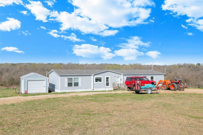 Manufactured / mobile home with driveway, a front lawn, roof with shingles, an outdoor structure, and a garage | Image 10