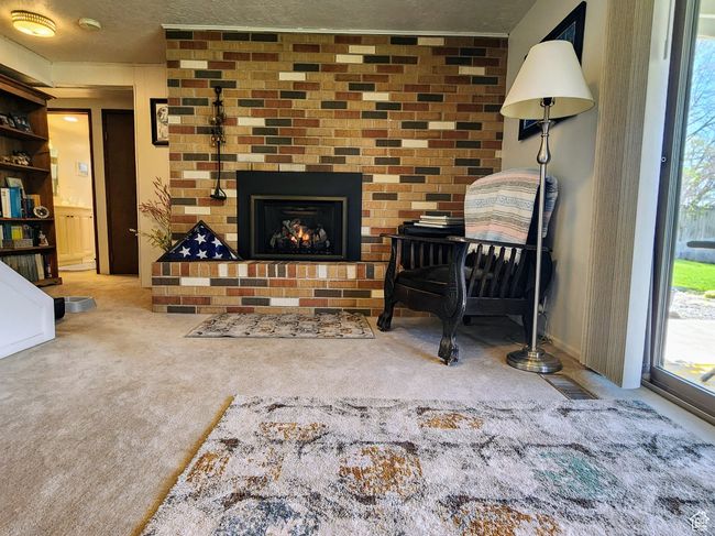 Carpeted living room featuring a textured ceiling and a brick fireplace | Image 30