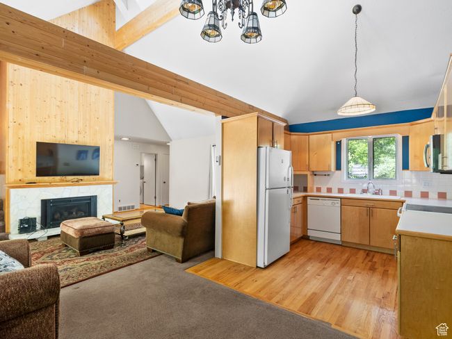 Kitchen with white appliances, open floor plan, light countertops, and hanging light fixtures | Image 4